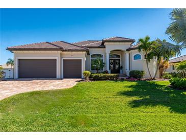 Beautiful home featuring a well-manicured lawn, a two-car garage, and lush tropical landscaping at 347 Portofino Dr, Punta Gorda, FL 33950