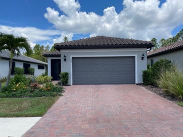 Charming single-story home featuring a brick driveway, attached two-car garage, and lush landscaping at 1352 Raspberry Dr, North Port, FL 34289