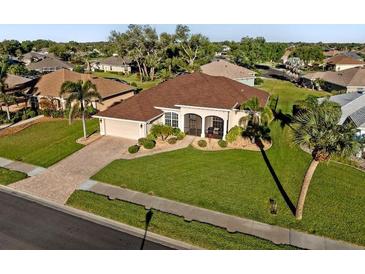 Well maintained single-story home with a lush lawn, mature landscaping, and a brick paved driveway at 2363 Jasmine Way, North Port, FL 34287