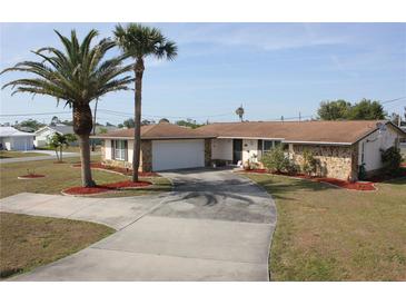 Charming single-story home featuring a stone accent, well-manicured lawn, and a circular driveway leading to an attached garage at 474 Elm Nw Ave, Port Charlotte, FL 33952
