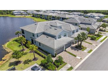 Stunning aerial view of a luxury townhome community on a lake with lush landscaping and paver driveways at 14617 Sycamore Ct # 2211, Punta Gorda, FL 33955