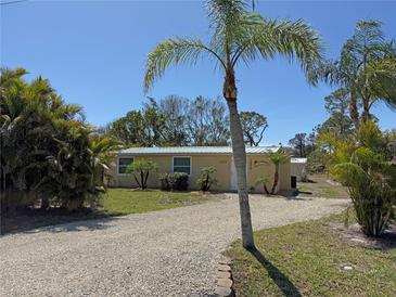 Charming single-story home with gravel drive, tropical landscaping, and sunny skies at 1270 Manor Rd, Englewood, FL 34223