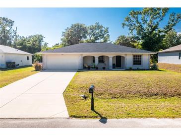 Charming single-story home with a well-manicured lawn, attached garage, and inviting front porch with decorative columns at 2903 Pope St, North Port, FL 34287