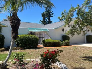 Charming home featuring a gated front entrance, lush greenery, and a well-maintained lawn at 1305 Alton Rd, Port Charlotte, FL 33952