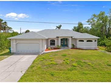 Charming single-story home with a well-manicured lawn, attached garage, and a welcoming blue front door at 13235 Essman Ave, Port Charlotte, FL 33953