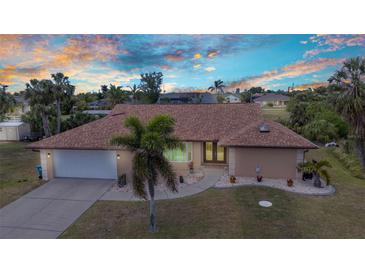 Beautiful single-story home with a well-manicured lawn, mature palms, and a two-car garage at sunset at 4473 Sweetbay St, Port Charlotte, FL 33948