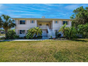 Inviting two-story condo building featuring lovely landscaping and a well-maintained lawn under a clear blue sky at 1051 Forrest Nelson Blvd # 104, Port Charlotte, FL 33952
