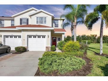 Charming two-story home boasts a red door, manicured landscaping, and a one-car garage at 1085 Jonah Dr, North Port, FL 34289