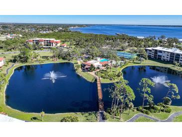 Stunning aerial view of the community, showing lush landscaping, serene ponds with fountains, and the adjacent waterfront at 23465 Harborview Rd # 925, Punta Gorda, FL 33980