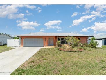 Charming single Gathering home with an attached garage, arched entry and nicely maintained landscaping in the front yard at 3187 Elkcam Blvd, Port Charlotte, FL 33952