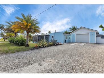 Charming light-blue single-story home with a gravel driveway and detached one car garage, accented by mature palm trees at 3215 Cedarbrook Dr, Punta Gorda, FL 33982