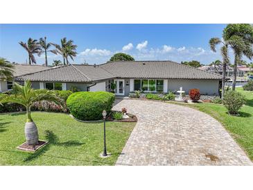 Charming home featuring a beautifully landscaped front yard, a fountain, and a circular paver driveway at 505 Via Cintia, Punta Gorda, FL 33950