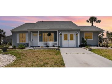 Charming single-story home featuring a well-manicured lawn and a cozy front porch with white picket fence at 5121 Chaves Cir, Port Charlotte, FL 33948