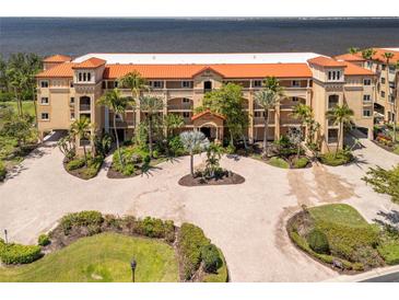 Beautiful waterfront condo building with lush landscaping and a circular brick paved driveway at 93 Vivante Blvd # 9344, Punta Gorda, FL 33950
