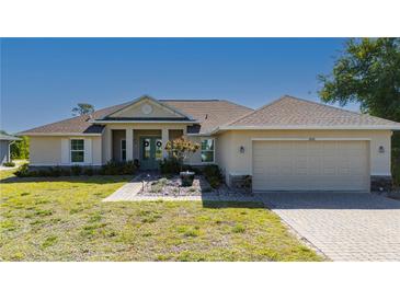 Charming single-story home featuring a landscaped front yard, a two-car garage, and a covered entryway with double doors at 1606 Navigator Rd, Punta Gorda, FL 33983