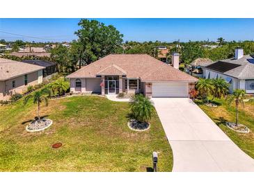 Charming single-story home with a well-manicured lawn, complemented by mature trees and a long driveway at 452 Greenwich Nw Ave, Port Charlotte, FL 33952