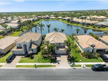 Stunning aerial view of a lakeside home with a tile roof, lush landscaping and a beautiful lake view at 11663 Anhinga Ave, Venice, FL 34292