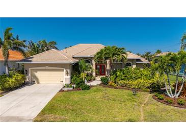 Beautiful single-story home featuring lush landscaping, well manicured lawn, and a tile roof with a two car garage at 211 Lido Dr, Punta Gorda, FL 33950