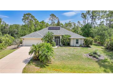Inviting single-story home featuring a well-manicured lawn, lush landscaping, and a light neutral-toned exterior at 2666 Barry Rd, North Port, FL 34286