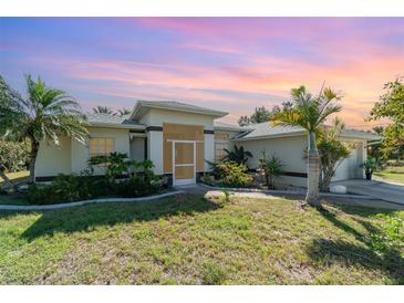 Charming home featuring a manicured lawn, screened front entrance, and lush tropical landscaping at 4010 Yucatan Cir, Port Charlotte, FL 33948