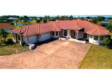 Spacious waterfront home featuring a large driveway, tile roof, and attached garages at 730 Boundary Blvd, Rotonda West, FL 33947
