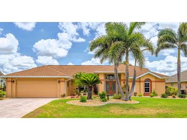 Charming single-story home with well-manicured lawn, tropical landscaping, and inviting double-door entry at 2202 Peterborough Rd, Punta Gorda, FL 33983