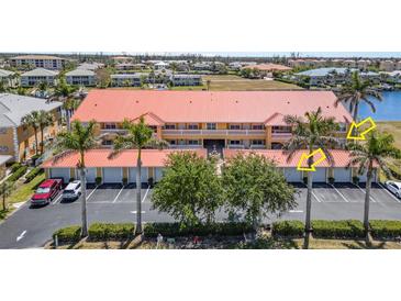 Condo building exterior with parking, landscaping, palm trees, and partial water view at 3228 Purple Martin Dr # 116, Punta Gorda, FL 33950