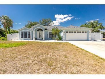Charming one-story home with a two-car garage, light blue exterior paint, and well-manicured landscaping at 4569 Kenvil Dr, North Port, FL 34288