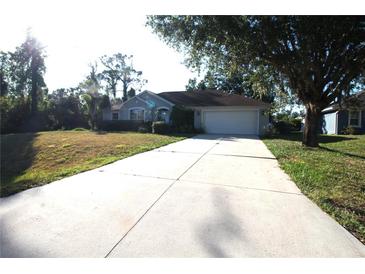 Charming single-story home with a well-manicured lawn and a long driveway leading to an attached two-car garage at 4749 Oakley Rd, North Port, FL 34288