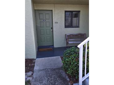 Inviting condo entrance with a green front door, bench, and a small garden at 25225 Rampart Blvd # 1801, Punta Gorda, FL 33983