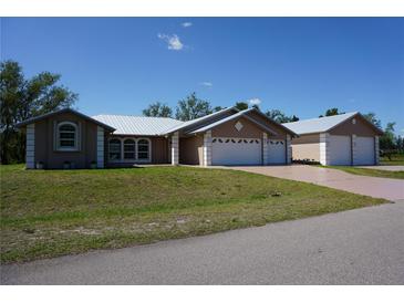 Charming single-story home featuring a metal roof and three-car garage in a well-manicured yard at 29211 Picador St, Punta Gorda, FL 33982