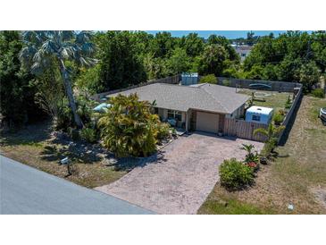 Charming single-story home with a brick-paved driveway and lush tropical landscaping, enclosed by a wooden fence at 3051 Chicory Ter, Punta Gorda, FL 33983