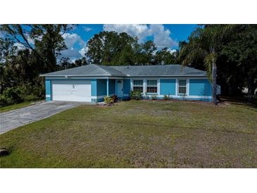 Charming single-story home featuring a blue exterior, well-maintained lawn, and attached two-car garage at 3175 Lakatos St, North Port, FL 34286