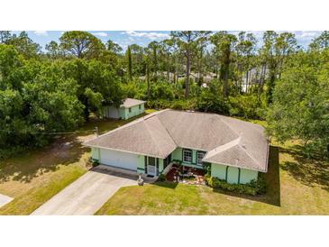 This single-story home has a well-manicured lawn, charming details, and a peaceful, tree-filled backdrop at 4461 La France Ave, North Port, FL 34286