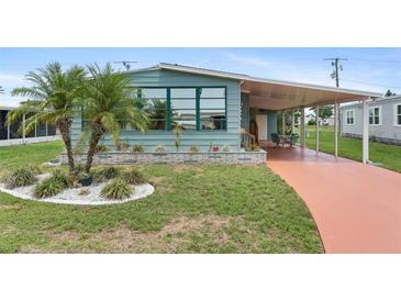 Charming home featuring a well-maintained yard with palm trees, a covered porch, and a vibrant painted driveway at 58 Lakeview Dr, North Port, FL 34287