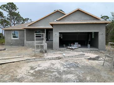 Under construction single-story house with open garage, light grey stucco, and visible materials at 135 Hardee Way, Rotonda West, FL 33947