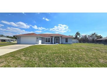 Charming single-story home with a well-manicured lawn, attached garage, and inviting screened front entry at 18519 Alphonse Cir, Port Charlotte, FL 33948