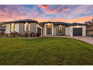 New construction home with black trim, modern design, three car garage, and fresh green lawn at 3729 Peace River Dr, Punta Gorda, FL 33983