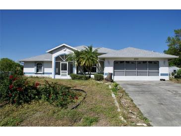 Charming single Gathering home with a two car garage, mature landscaping, and blue accents at 5050 Prosch Cir, North Port, FL 34288