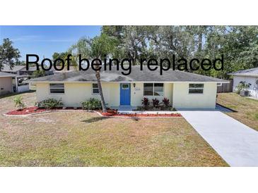 Inviting single-story home featuring a vibrant blue front door, well-maintained lawn, and lovely landscaping at 20215 Macon Ln, Port Charlotte, FL 33952