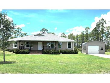 Charming single-story home with covered porch, green lawn and a detached garage or shed on a sunny day at 6405 Alan Blvd, Punta Gorda, FL 33982