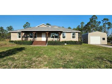 Inviting home featuring a covered front porch, lush lawn, and detached garage at 6405 Alan Blvd, Punta Gorda, FL 33982