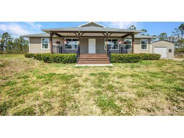 Charming home featuring a welcoming front porch, complemented by lush greenery and a manicured lawn at 6405 Alan Blvd, Punta Gorda, FL 33982