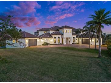 Elegant two-story home boasts a manicured lawn, tile roof, and multiple garages for ample parking at 10580 Poughkeepsie Cir, Port Charlotte, FL 33981