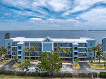 Beautiful waterfront condo building with blue exterior, multiple balconies, palm trees and ample parking at 1750 Jamaica Way # 312, Punta Gorda, FL 33950