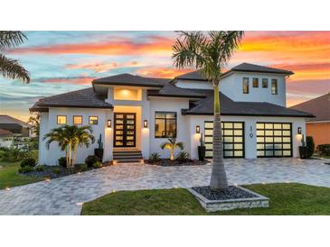 Stunning exterior of a modern home featuring a well-manicured lawn, palm trees, and decorative driveway pavers at sunset at 19 Sabal Dr, Punta Gorda, FL 33950