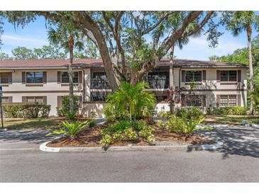Charming condo building featuring mature trees, lush landscaping, and ample parking at 19505 Quesada Ave # A204, Port Charlotte, FL 33948