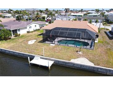 Aerial view of screened-in pool and dock in backyard on a waterfront property surrounded by mature landscaping at 425 Belvedere Ct, Punta Gorda, FL 33950