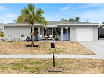 Charming single-story home with a well-manicured lawn, a light blue door, and an attached garage at 6531 Marius Rd, North Port, FL 34287