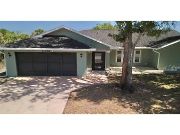 Inviting one story home featuring an attached two-car garage, lush landscaping and inviting front entrance at 17356 Gulfspray Cir, Port Charlotte, FL 33948